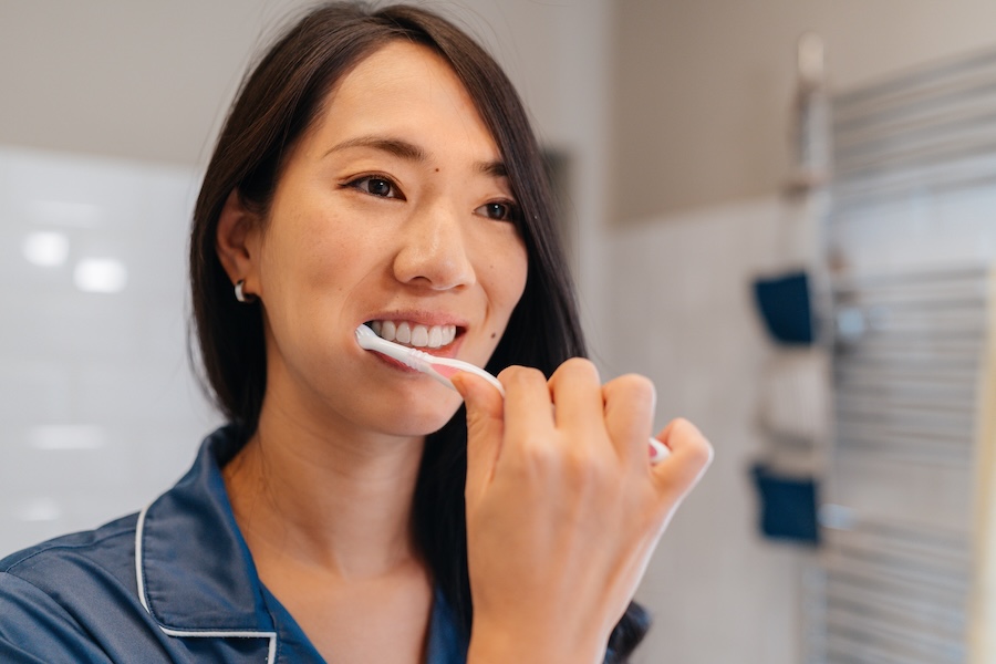 woman brushing teeth to maintain cosmetic dental work